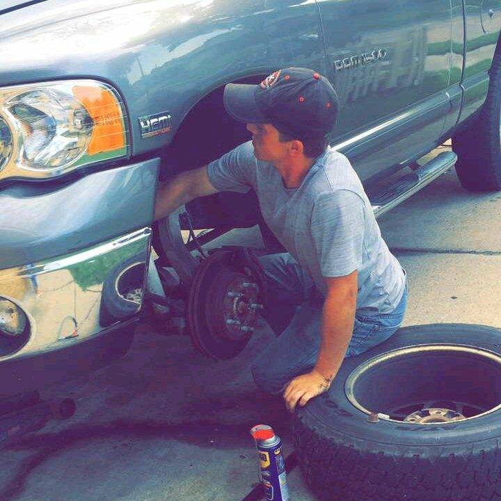 Person changing a tire on a truck with a can of tire pressure gauge nearby.