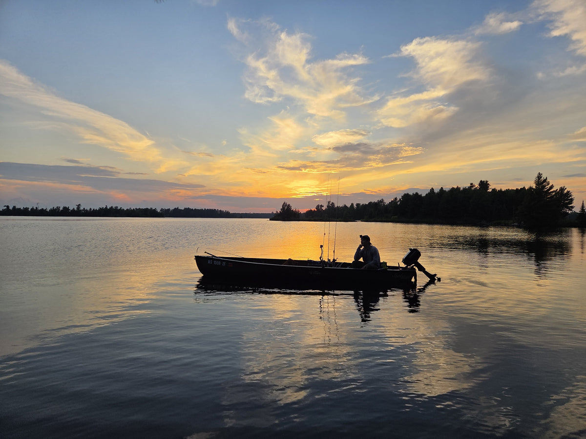 Nicholas Piparo in a boat on the turtle flambeau flowage in northern Wisconsin at sunset with a colorful sky.