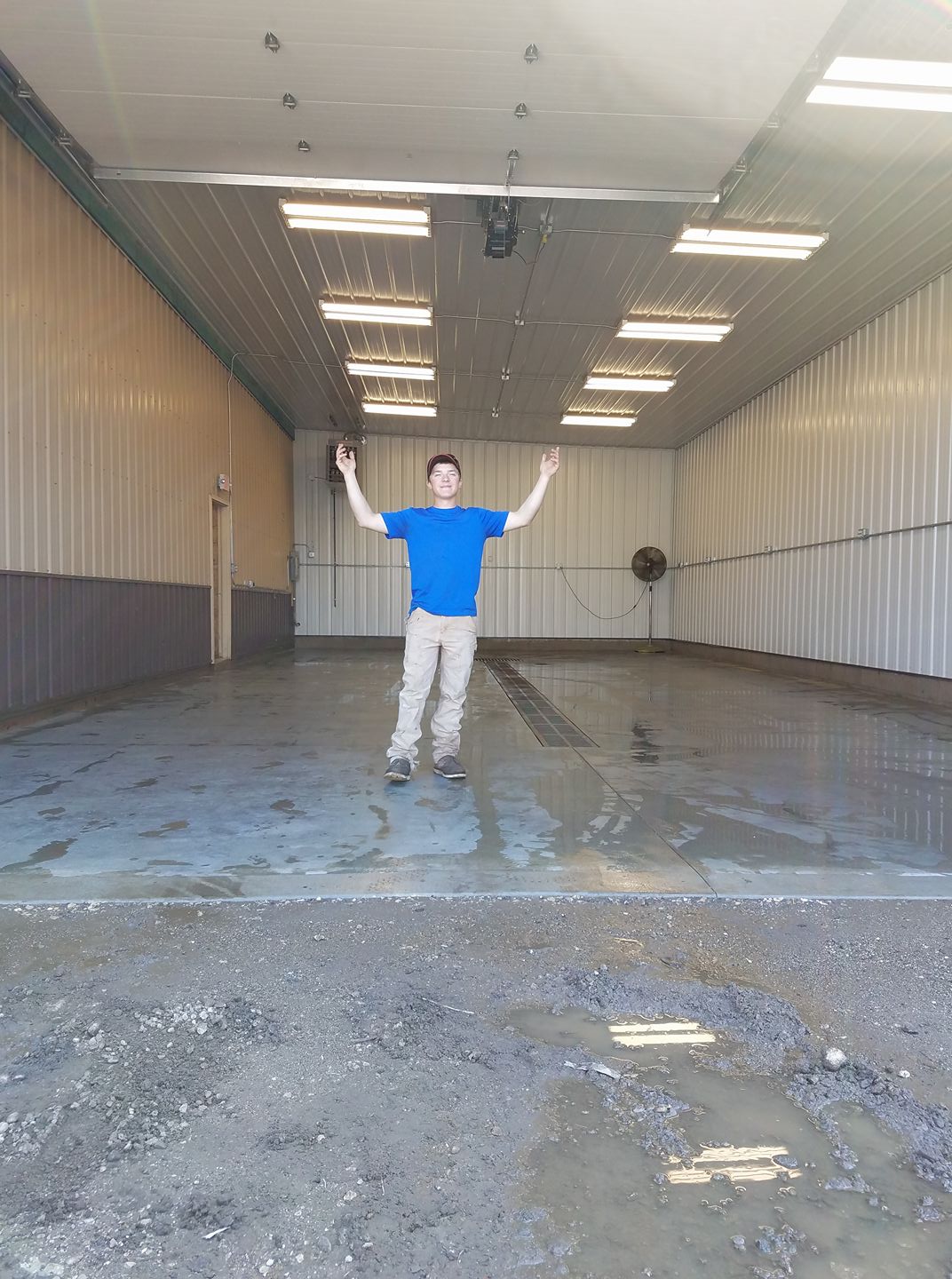 Person standing in a large empty warehouse with concrete floor and metal walls.